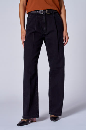 Zwarte wide jeans van Astrid Black Label, met plooien en een zwarte riem gedragen, gecombineerd met bruine top en zwarte schoenen.
