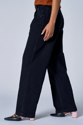 Jean délavé noir d'Astrid Black Label, vu sur le côté avec des chaussures noires assorties.