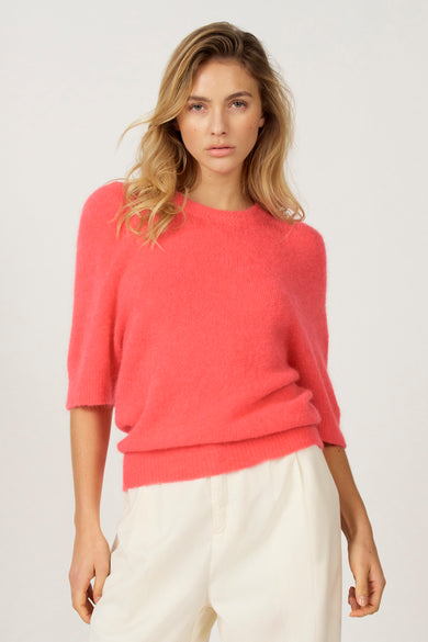 Roze trui met ronde hals van Astrid Black Label, gedragen met een witte broek.
