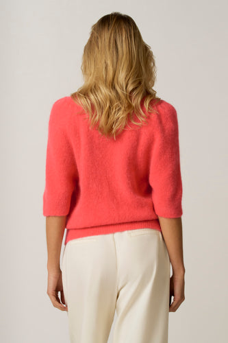 Roze trui met ronde hals van Astrid Black Label, gezien van achteren, met crèmekleurige pantalon.
