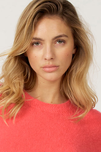 T-shirt rose avec col rond d'Astrid Black Label, en tissu doux et porté par une femme.