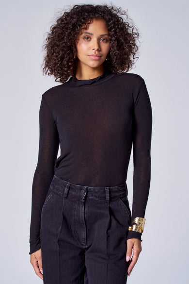 T-shirt noir à manches longues d'Astrid Black Label, associé à un pantalon noir et une bague de bras dorée.