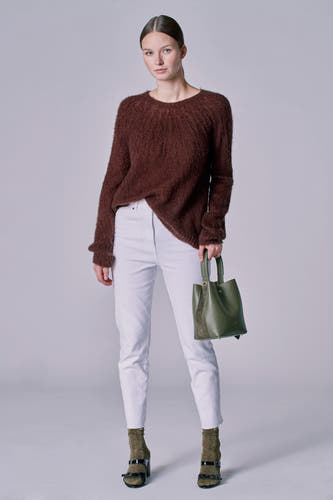 Jean 7/8 blanc d'Astrid Black Label, porté avec un pull marron et une poche verte.