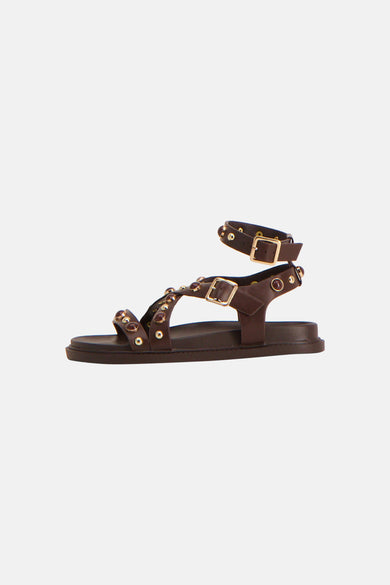 Bruine sandalen van Astrid Black Label met bandjes, goudkleurige gespen en decoratieve stenen, in zijaanzicht.
