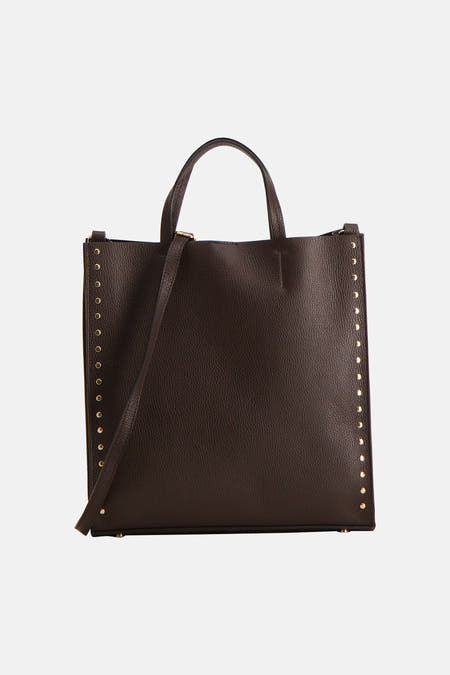 Bruine handtas van leer van Astrid Black Label, met lange schouderband en gouden studs langs de zijkanten.