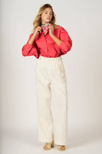 Roze hemd met lange mouwen van Astrid Black Label, met een sjaaltje en gecombineerd met een witte pantalon.
