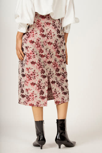 Roze rok van Astrid Black Label met een bloemenpatroon en een split aan de achterkant, gecombineerd met zwarte laarsjes en een witte blouse.
