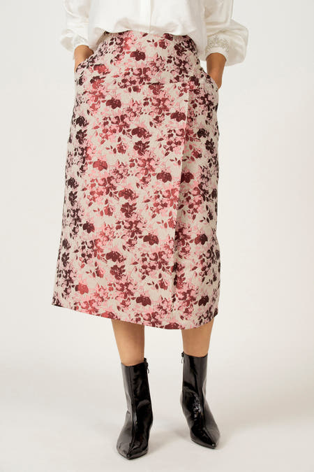 Robe rose d'Astrid Black Label avec imprimé de fleurs, poches et escarpins noirs.