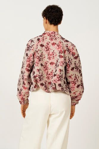 Manteau rose d'Astrid Black Label avec imprimé de fleurs, vu de derrière, combiné avec un pantalon blanc.