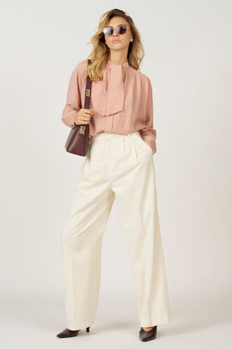 Blouse rose à longues manches d'Astrid Black Label, avec un col en forme de cœur et portée avec une jupe blanche.