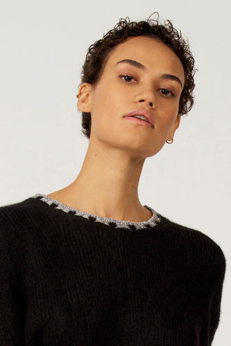 Portret van een vrouw in een zwarte trui met zilveren details rond de halslijn.