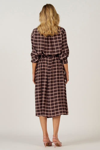 Bruine jurk met lange mouwen van Astrid Black Label, met ruitpatroon en een elastische tailleband.
