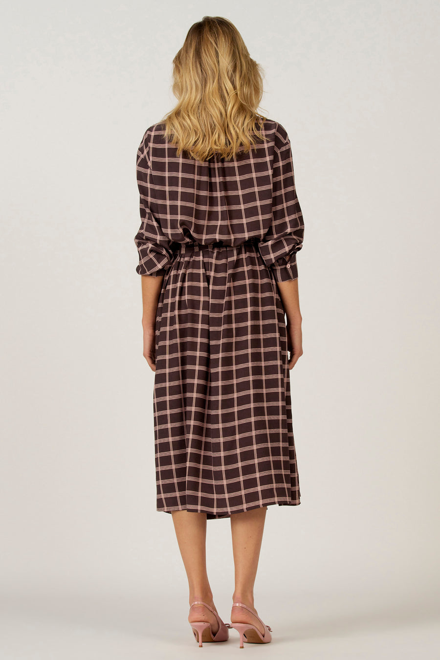 Bruine jurk met lange mouwen van Astrid Black Label, met ruitpatroon en een elastische tailleband.
