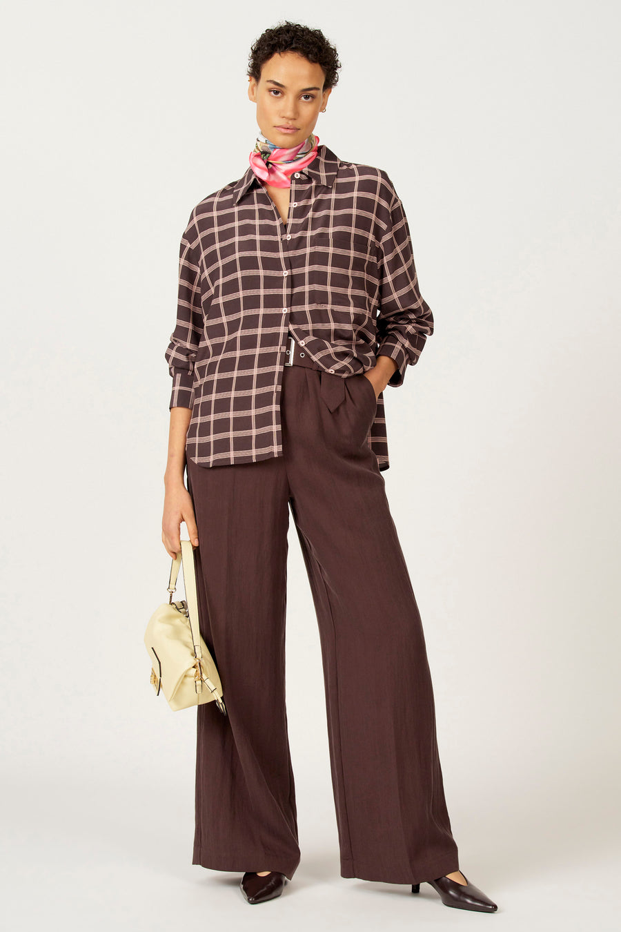 Blouse brune à longues manches d'Astrid Black Label, avec un motif de carreaux et une écharpe en soie autour du cou.