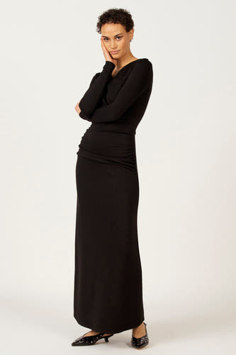 Robe noire à longues manches d'Astrid Black Label, avec des détails plissés et des chaussures noires assorties.