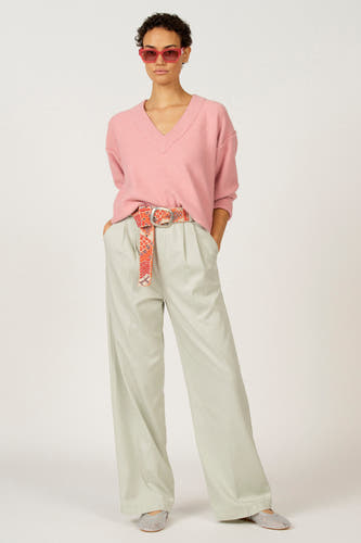 T-shirt rose à col V d'Astrid Black Label, porté avec un pantalon à larges pinces et une ceinture imprimée.
