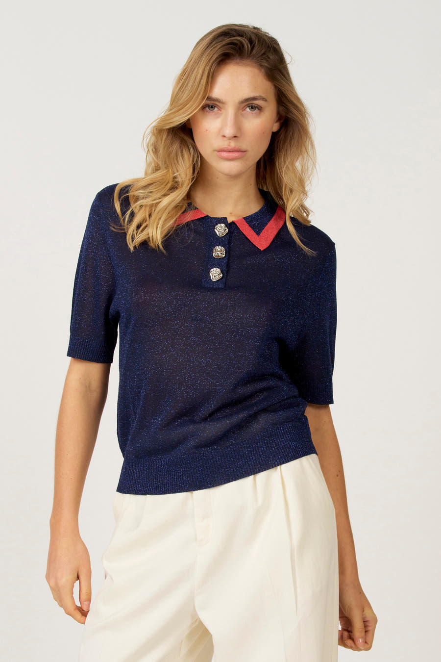 Blauwe polo met korte mouwen van Astrid Black Label, met rood detail op de kraag en decoratieve knopen.
