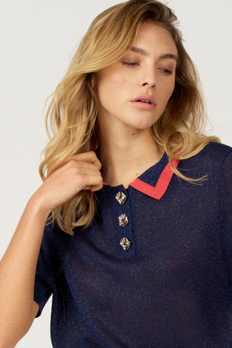 Polo bleu à manches courtes d'Astrid Black Label avec des boutons décoratifs et des accents rouges sur la patte de col.