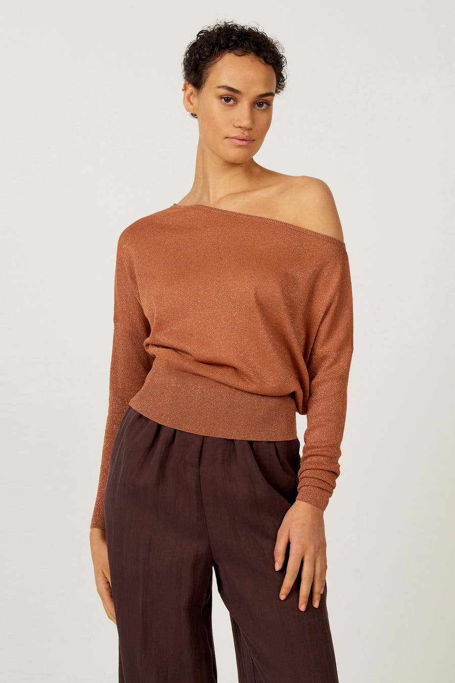 Oranje trui van Astrid Black Label, met lange mouwen en gedragen met bruine pantalon.
