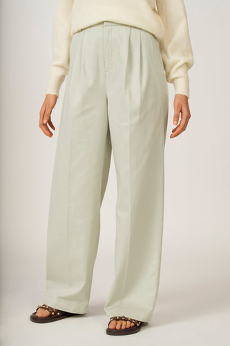 Groene colorbroek van Astrid Black Label, met plooien en wijde pijpen, gecombineerd met een gebreide trui en sandalen.