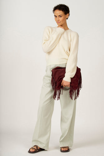 Groene colorbroek van Astrid Black Label, gedragen met een crèmekleurige trui en bruine sandalen met studs.