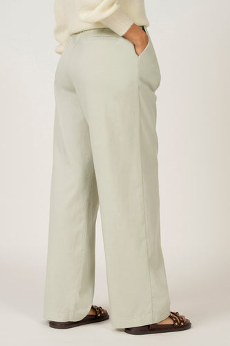 Groene colorbroek van Astrid Black Label, met steekzak en wijde pijpen, gedragen met een gebreide trui en sandalen.
