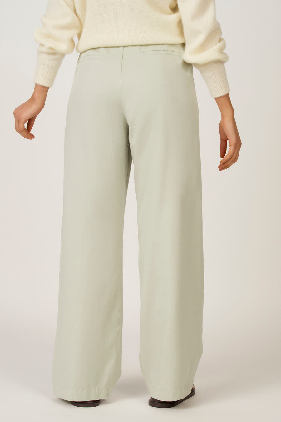 Groene colorbroek van Astrid Black Label, gezien van achteren, gecombineerd met een ecrukleurige trui.
