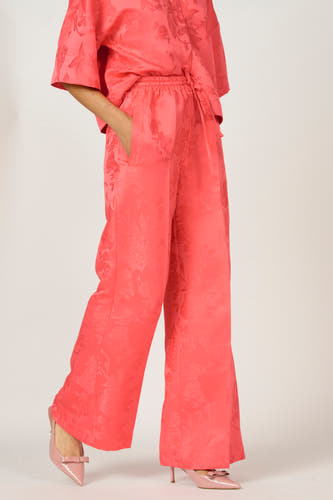 Roze broek van Astrid Black Label met bloemenpatroon en bijpassende hakken met strik.
