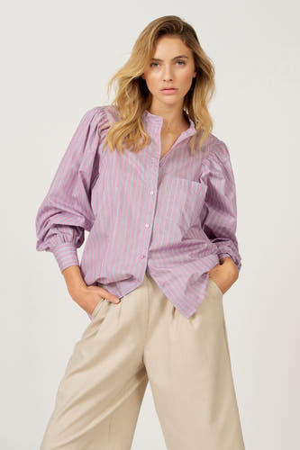 Chemise rose à manches longues Astrid Black Label, avec un motif rayé et des manches bouffantes, sur un pantalon beige.