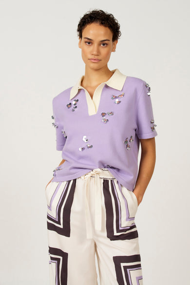 Polo marron avec manches courtes d'Astrid Black Label, avec col blanc et imprimé graphique sur la jupe.