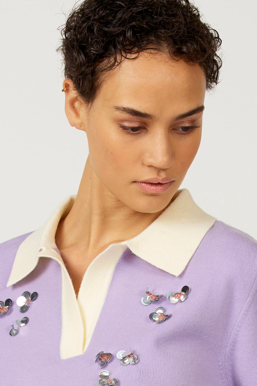 Paarse polo met korte mouwen van Astrid Black Label, versierd met bloemvormige pailletten en een witte kraag.