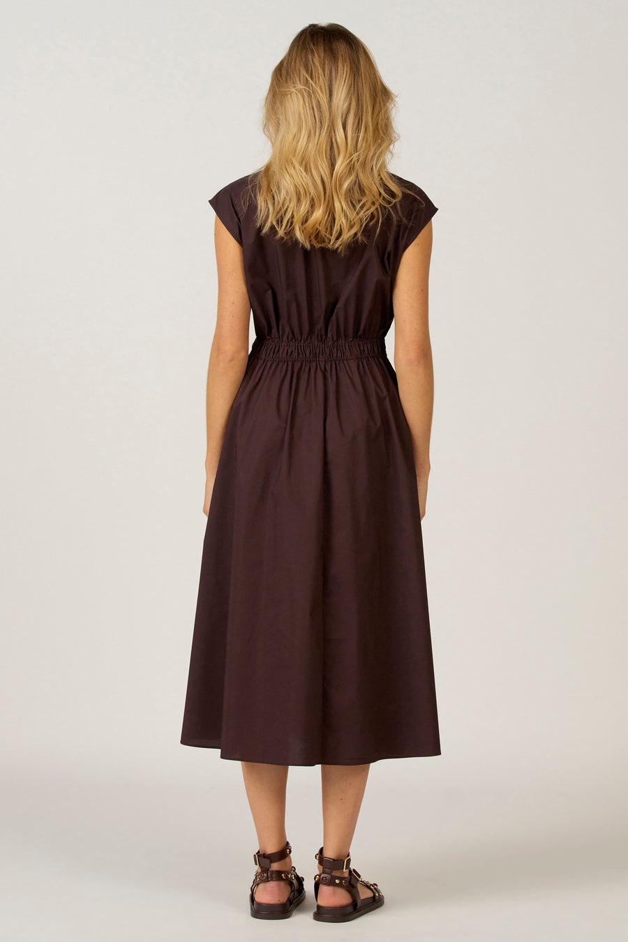 Robe sans manches Astrid Black Label, vue de derrière, avec une taille élastique et une longueur genouillère, portée avec des sandales.