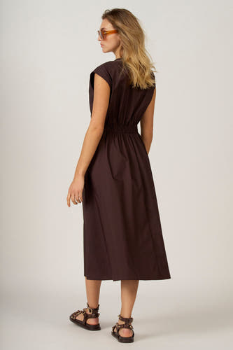Bruine kleedje zonder mouwen van Astrid Black Label, met elastiek in de taille en enkelhoge sandalen.
