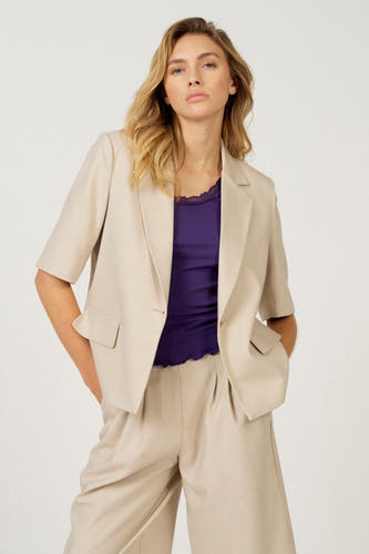 Ecru blazer van Astrid Black Label, gedragen met een paarse top met kanten rand en bijpassende broek.