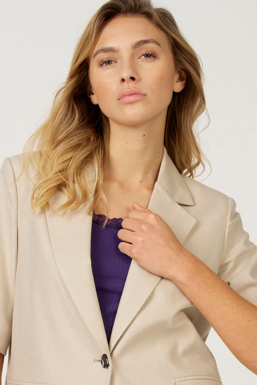 Ecru blazer van Astrid Black Label, gedragen over een paarse top met kanten details.
