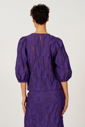 Paarse blouse met driekwart mouwen van Astrid Black Label, met een reliëf bloempatroon en een knoopsluiting aan de achterkant.