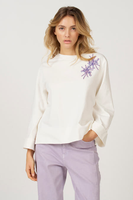 Ecru T-shirt met lange mouwen van Astrid Black Label, met sierlijke paarse borduursels op de schouder.