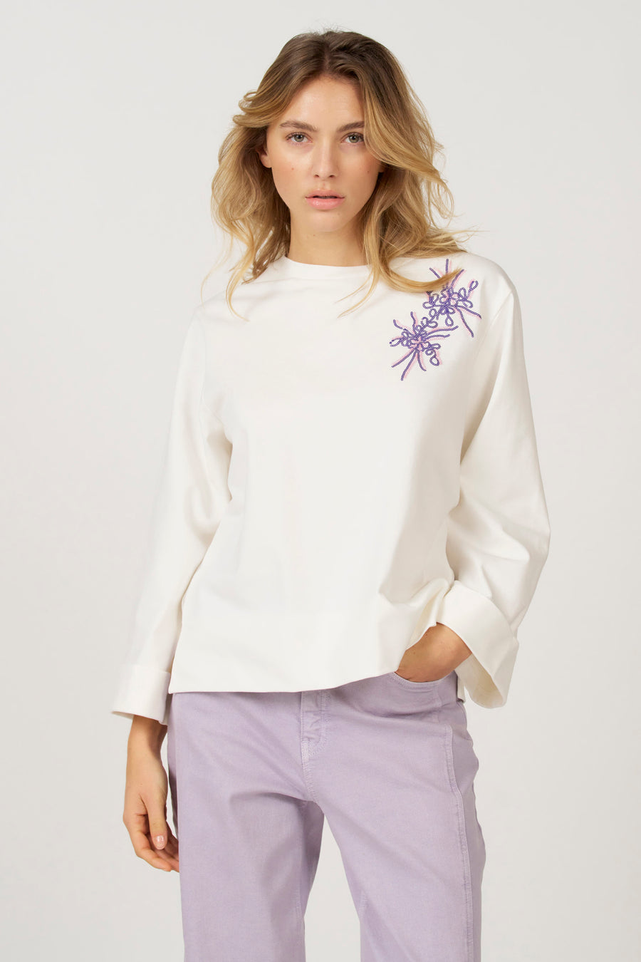 Ecru T-shirt met lange mouwen van Astrid Black Label, met sierlijke paarse borduursels op de schouder.