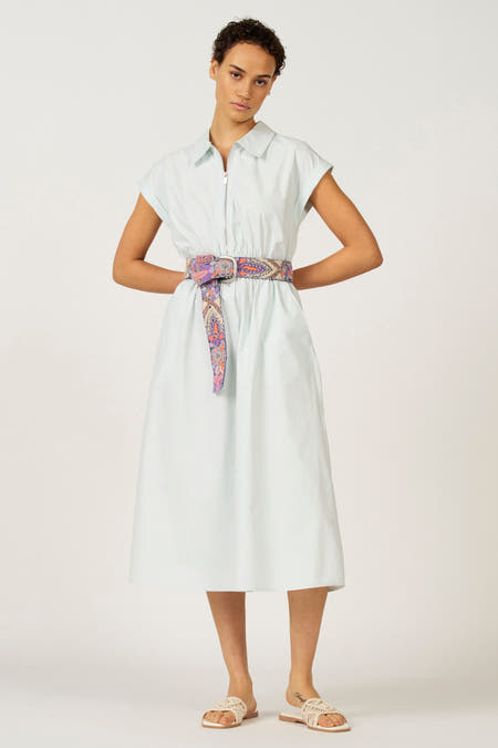 Jupe sans manches bleue d'Astrid Black Label, avec une ceinture colorée, des poches et des sandales.