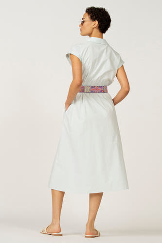 Blauwe mouwloze jurk van Astrid Black Label, met kleurrijke riem, zakken en sandalen.