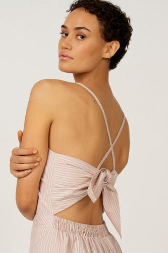 Robe rose sans manches d'Astrid Black Label, avec motif rayé et bretelles croisées et nœud dans le dos.