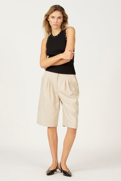 Zwarte singlet van Astrid Black Label, met zilverkleurige studs langs de halslijn, gedragen met kaki culotte en zwarte ballerina's.
