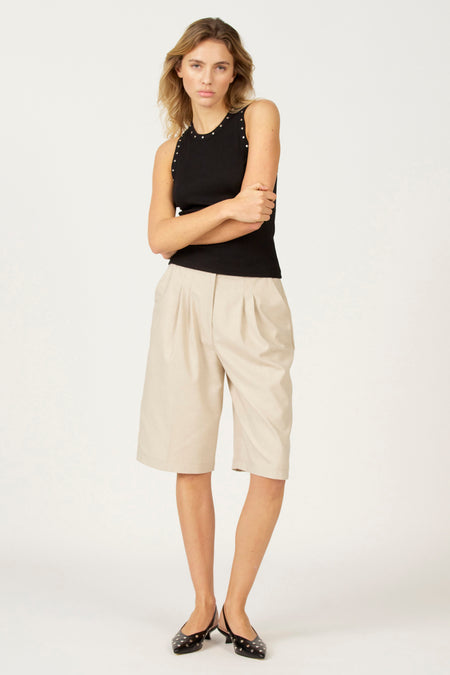 Zwarte singlet van Astrid Black Label, met zilverkleurige studs langs de halslijn, gedragen met kaki culotte en zwarte ballerina's.
