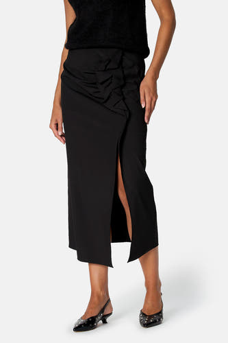 Jupe noire midi Astrid Black Label portée, avec volants à l’avant et fente sur le devant.