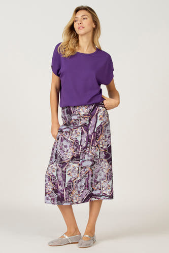 Blouse rose à col rond d'Astrid Black Label, associée à une jupe imprimée et des chaussures argentées.