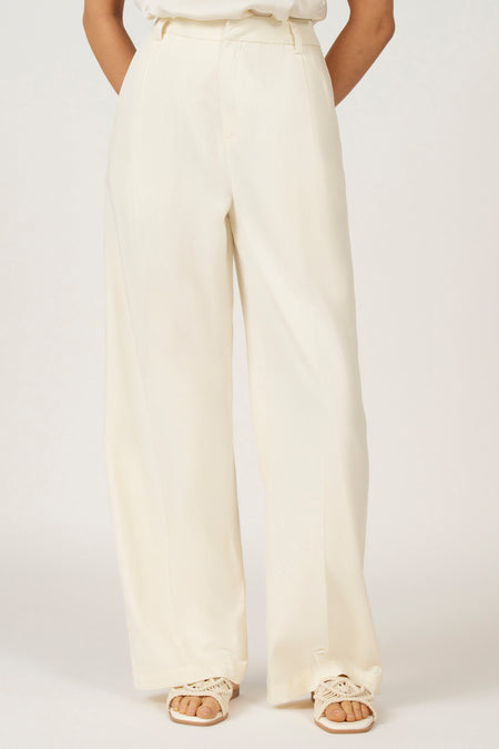 Ivoorwitte, wijde broek van stof, met sandalen.