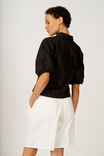 Zwarte blouse met driekwart mouwen van Astrid Black Label, getoond vanuit de achterkant, gecombineerd met een witte broek.