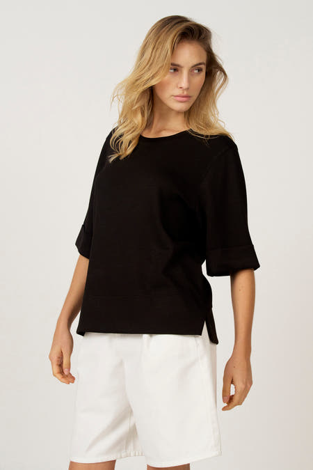 Zwart T-shirt met korte mouwen van Astrid Black Label, gecombineerd met een witte short.
