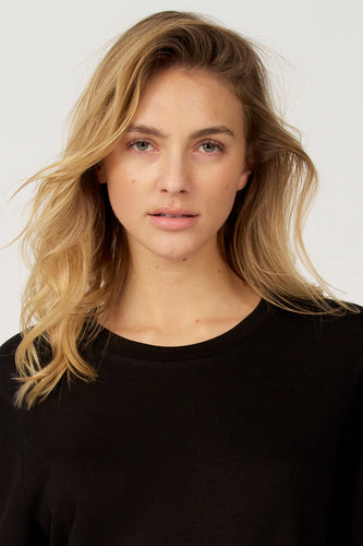 Zwart T-shirt met korte mouwen van Astrid Black Label, gedragen met los, blond haar.
