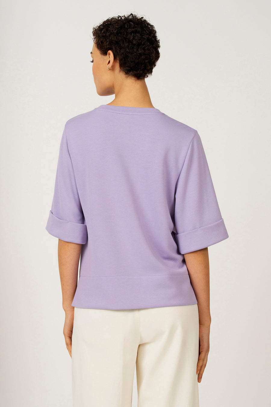 Paars T-shirt met korte mouwen van Astrid Black Label, met omgeslagen mouwen en gedragen met een witte broek.